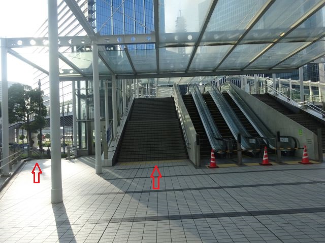 横浜駅からKアリーナ横浜のアクセス（日産グローバル本社ギャラリーを出たみなとみらい地区の景色・地上とデッキ方面2か所に赤い矢印）