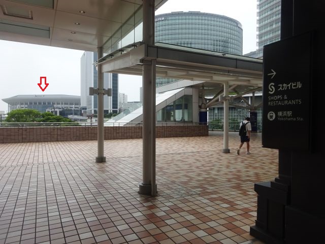 横浜駅からKアリーナ横浜のアクセス（横浜スカイビル2Fのペデストリアンデッキから見えるKアリーナ横浜に赤い矢印）