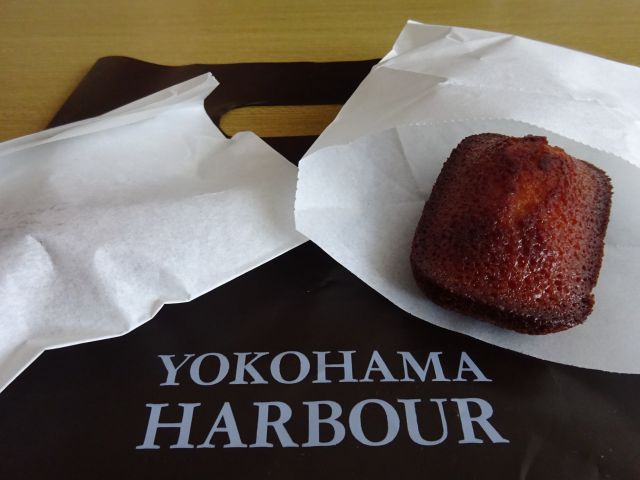 「レ・ザンジュ・ベイ・ヨコハマ山下本店」で購入した焼きたて鎌倉フィナンシェ(紙袋と紙袋を開けて鎌倉フィナンシェが見えるようにしている)