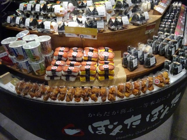 横浜駅にあるおにぎり専門店「ぼんたぼんたFOOD＆TIME ISETAN YOKOHAMA店」おにぎりセット、スパムにぎり、から揚げなどが並ぶ商品棚の様子