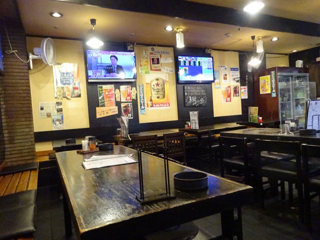 桜木町ぴおシティ「ゴールデンもつ」店内の様子（テーブル席が並んでおり灰皿が置かれている、壁にはテレビあり）