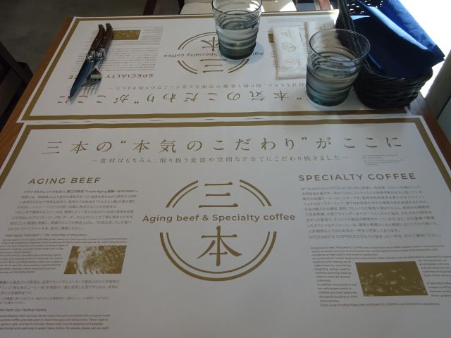 横浜みなとみらい「Aging Beef＆Specialty coffee THE三本」テーブル席にお店のこだわりが書かれたペーパーランチョンマットが敷いてある