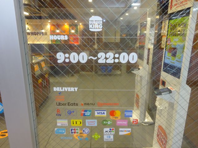 「バーガーキング相鉄横浜駅店」の入口から見える店内と扉に書かれた営業時間の案内など