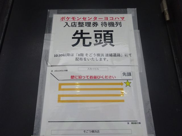 横浜スカイビル2階ペデストリアンデッキ「はまテラス」にて、ポケモンセンターヨコハマ入店整理券待機列の案内が壁に貼ってある