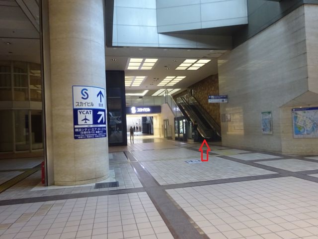 横浜スカイビル2階ペデストリアンデッキ「はまテラス」に行く地下ルート（スカイビル・YCATの矢印案内板あり、YCATとはまテラスに向かうエスカレーターに赤い矢印をつけている）